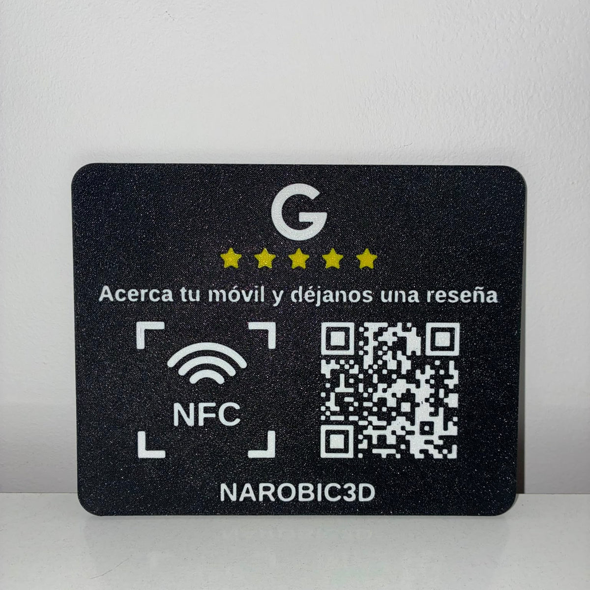 Placa de reseñas Google con NFC y QR apoyada en una pared blanca