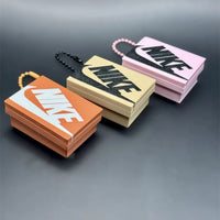 Tres modelos de llavero caja de zapatillas en naranja, crema y rosa