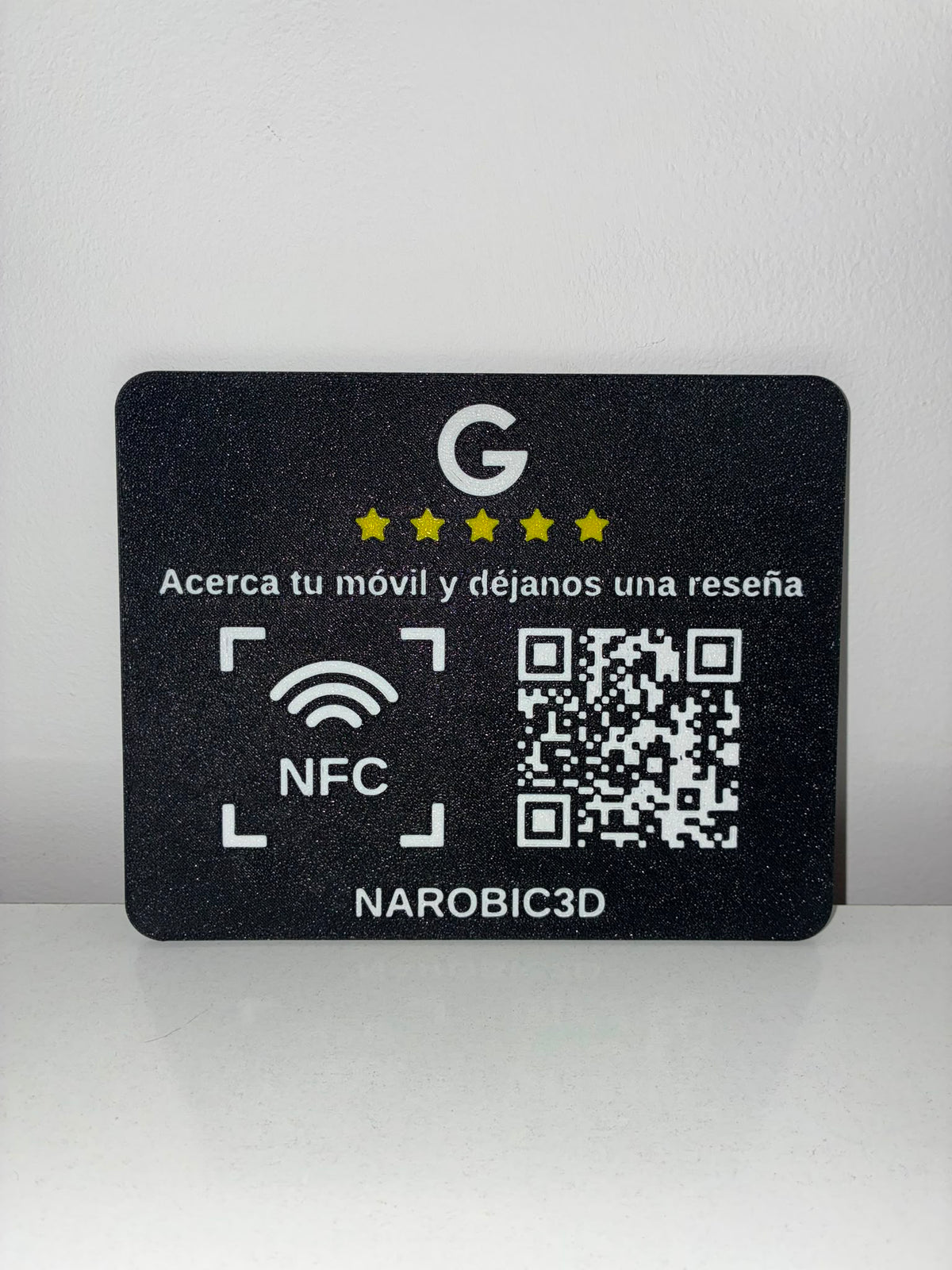 Placa de reseñas Google con NFC y QR apoyada en una pared blanca
