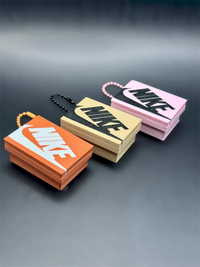 Tres modelos de llavero caja de zapatillas en naranja, crema y rosa